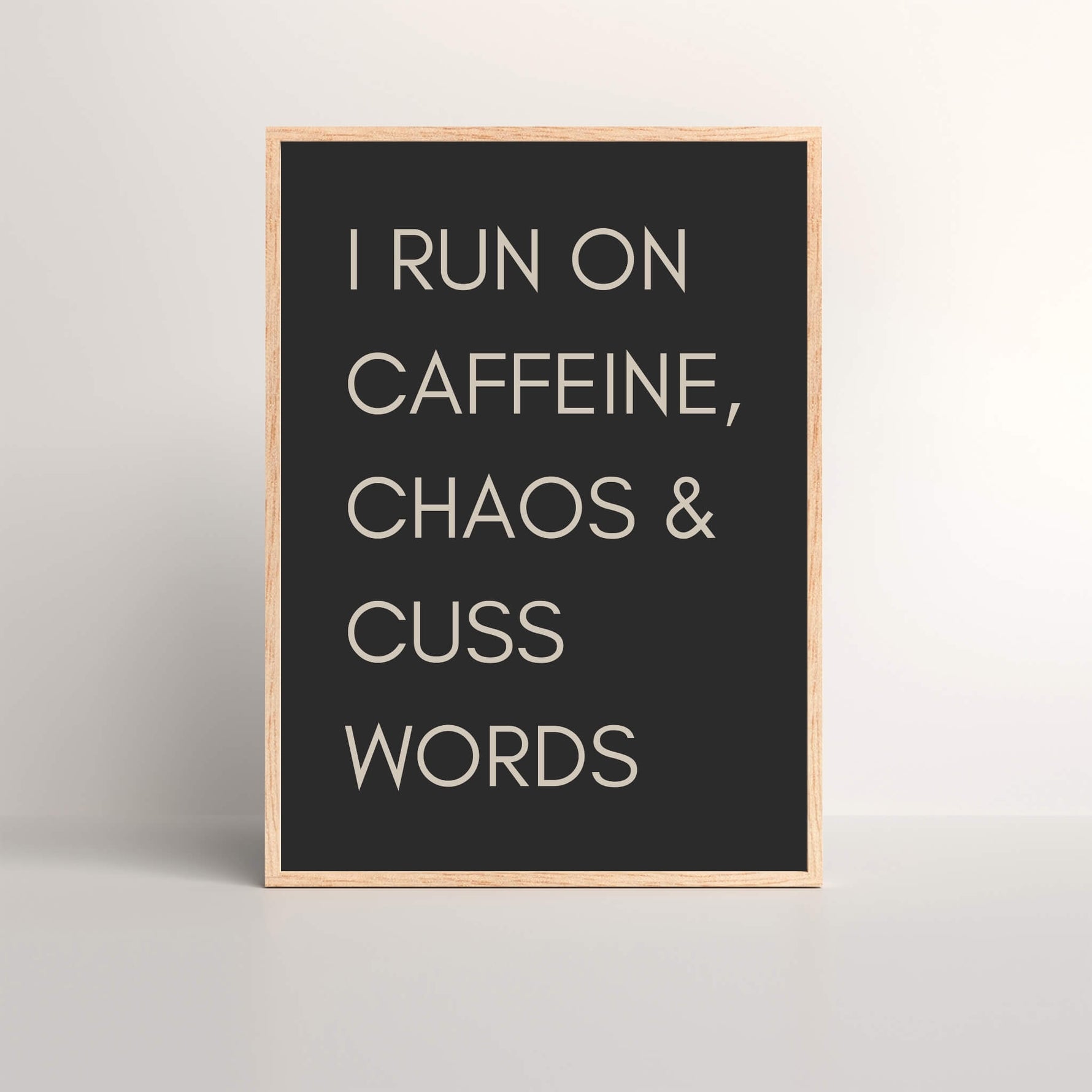 I Run On Caffeine, Chaos & Cuss Words Quote Wall Art Print with a dark back ground and cream font in an oak picture frame