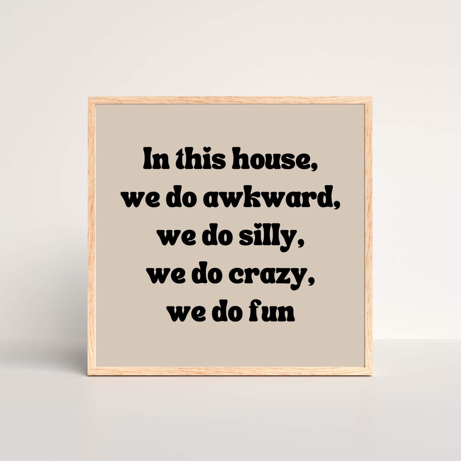 a black and beige oak framed art print with the words in this house, we do awkward, we do silly, we do crazy we do fun