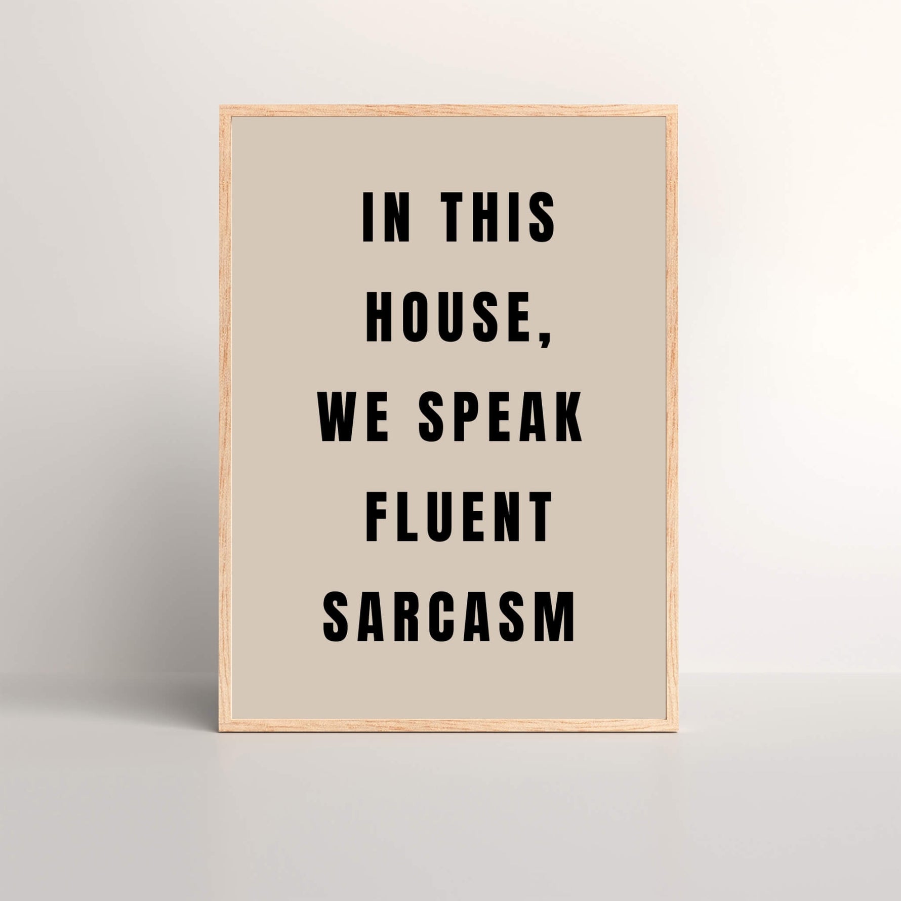 black and beige typography on an framed art print that says 'In This House, We Speak Fluent Sarcasm'